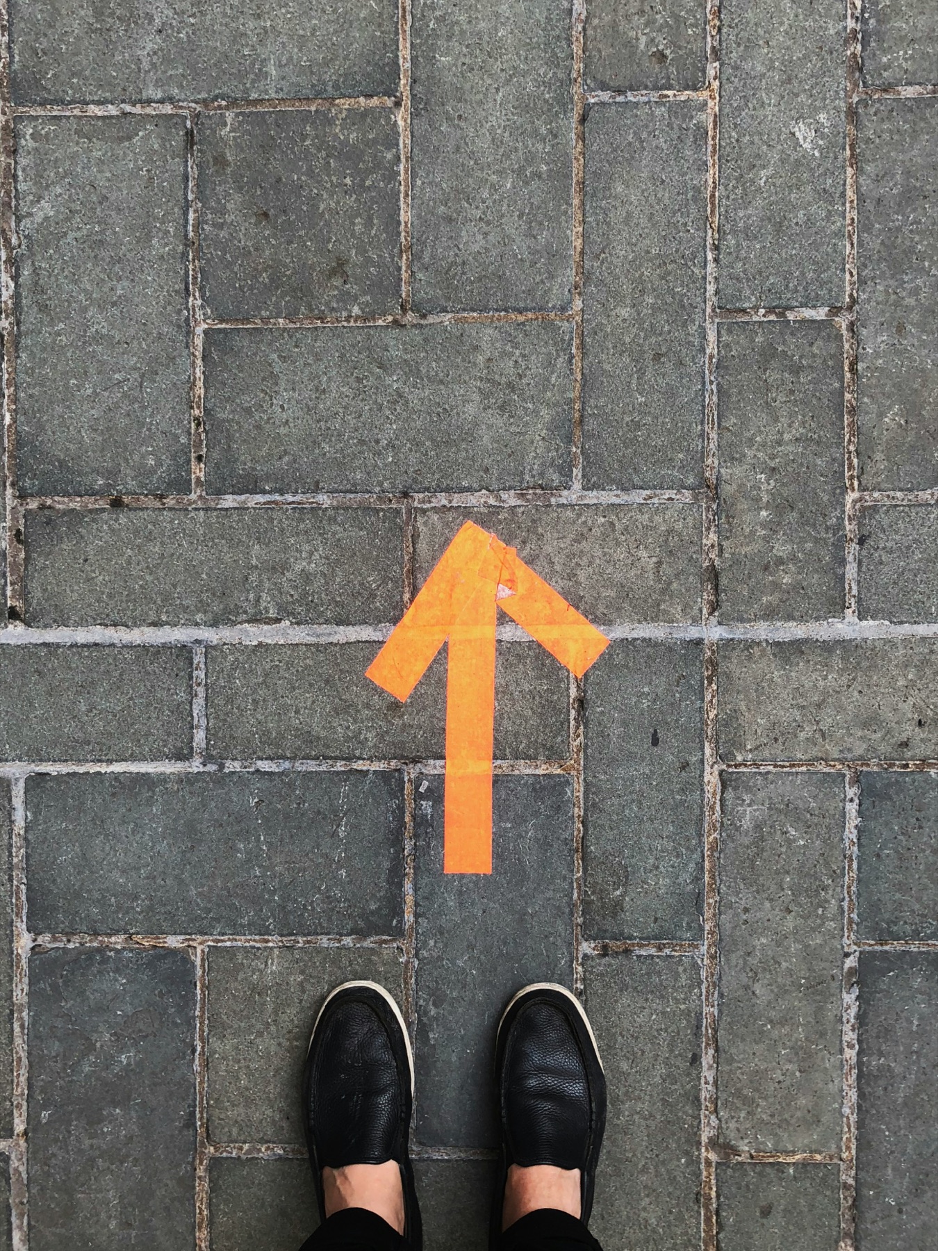 Orangefarbener Pfeil auf Steinboden als Bild fuer den naechsten Schritt